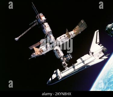 This view of the Space Shuttle Atlantis still connected to Russia's Mir Space Station was photographed by the Mir-19 crew on July 4, 1995. Cosmonauts Anatoliy Y. Solovyev and Nikolai M. Budarin, Mir-19 Commander and Flight Engineer, respectively, temporarily undocked the Soyuz spacecraft from the cluster of Mir elements to perform a brief fly-around. They took pictures while the STS-71 crew, with Mir-18's three crew members aboard, undocked Atlantis for the completion of this leg of the joint activities. Solovyev and Budarin had been taxied to the Mir Space Station by the STS-71 ascent trip of Stock Photo