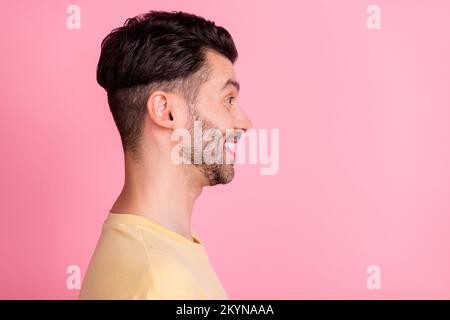 Side profile photo of optimistic satisfied man stylish haircut yellow t-shirt look empty space smiling isolated on pink color background Stock Photo