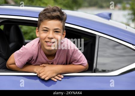 Portrait of excited boy leaning outside through car window Stock Photo