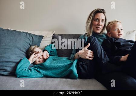 Woman spending leisure time with sons on sofa at home Stock Photo