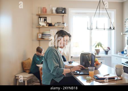 Smiling female freelancer working on laptop at home Stock Photo