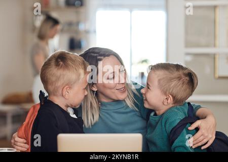 Mother with arms around sons talking to them at home Stock Photo