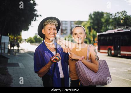 Portrait of happy non-binary person standing by young man wearing hat Stock Photo