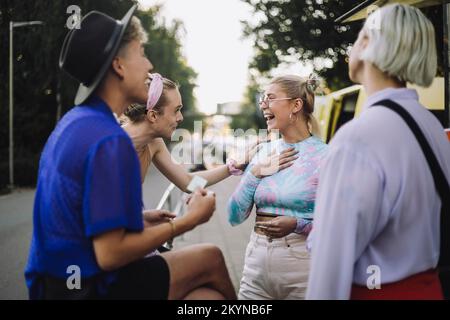 Cheerful woman wearing eyeglasses talking with non-binary friend Stock Photo