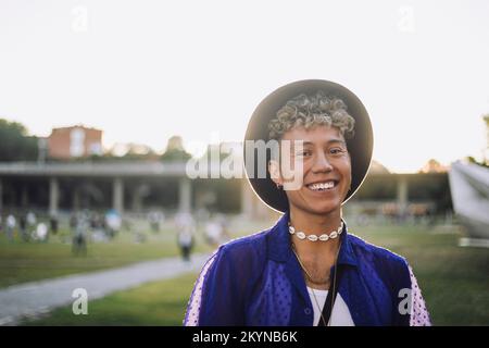 Portrait of happy young man with curly hair wearing hat at park Stock Photo