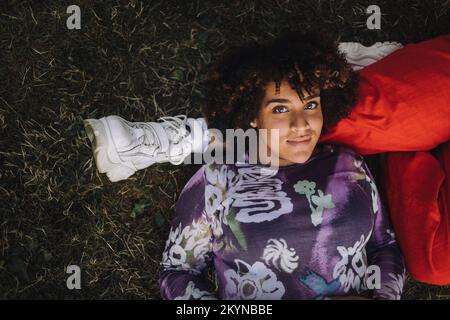 Portrait of smiling transgender woman lying on non-binary friend's leg Stock Photo