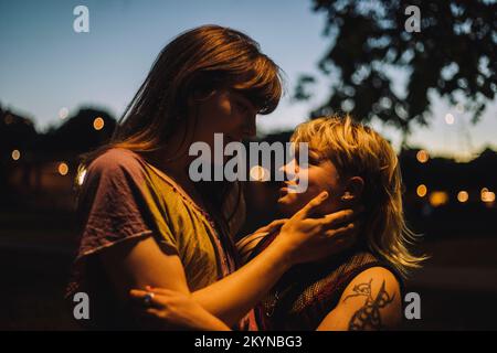 Young transgender woman looking at non-binary person at night Stock Photo
