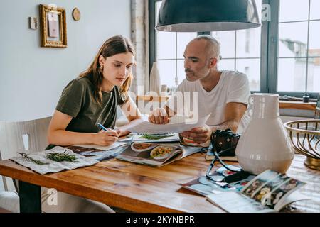 Business colleagues reviewing photograph while working at table in studio Stock Photo