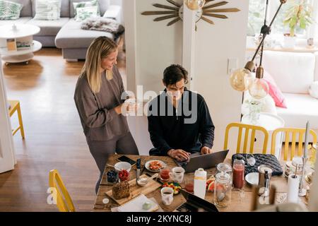 High angle view of happy couple having breakfast while working at home Stock Photo