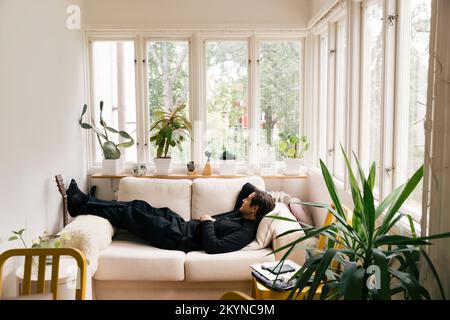 Side view of man sleeping on sofa in living room at home Stock Photo