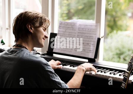 Passionate young man playing piano at home Stock Photo