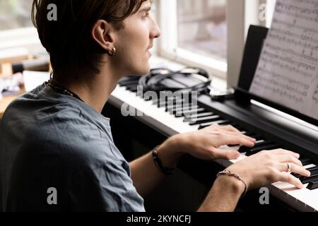 Concentrated young man practicing piano at home Stock Photo