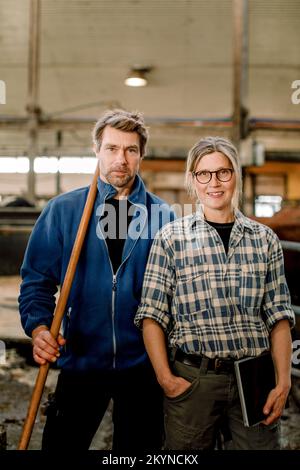 Smiling mature farmers standing together at cattle farm Stock Photo