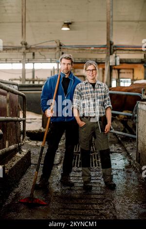 Smiling farmers standing together at cattle farm Stock Photo