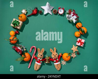 Christmas decorations: fir-tree toys, tangerines, gift boxes on green background. Merry Christmas and Happy New Year concept Stock Photo
