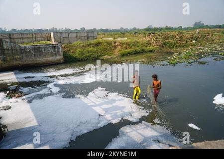 Two boys Catching fish with fishnet in indian sewer, water pollution, pollution control,Pollution concept Stock Photo