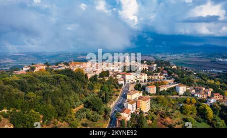 Chiusi village cityscape in Tuscany Italy with orange red rooftop tile houses on mountain countryside and rolling hills. Colorful evening in small tow Stock Photo