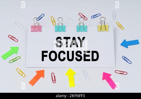 Business and finance concept. On the table there are paper clips and directional arrows, a sign that says - STAY FOCUSED Stock Photo