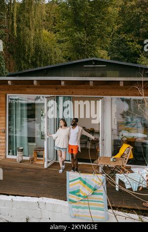 Multiracial couple standing together on porch at doorway Stock Photo