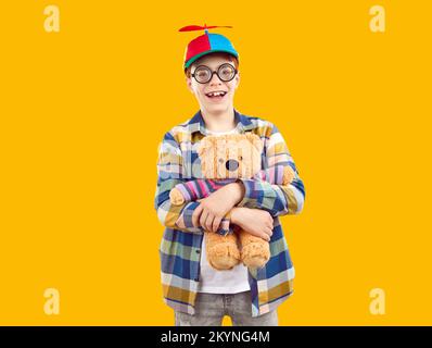 Happy school boy in propeller cap and funny glasses holding his teddy bear and smiling Stock Photo