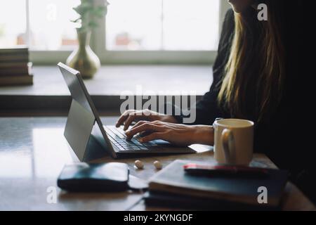 Hands of female entrepreneur typing on laptop at table in restaurant Stock Photo