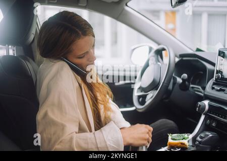 Female professional talking on smart phone while sitting in car Stock Photo