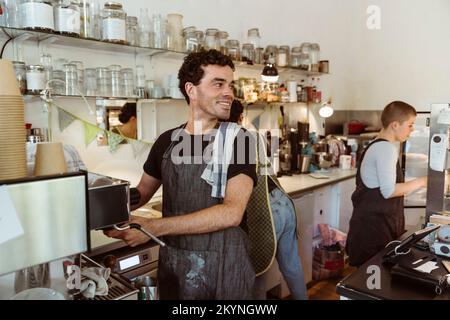 Smiling owner looking away while preparing coffee at cafe Stock Photo