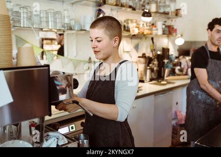 Young female barista preparing coffee at cafe Stock Photo