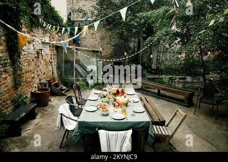 Food and drink set up on dining table in decorated back yard Stock Photo
