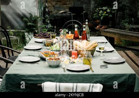Food and drink set up with plates arranged on dining table in back yard Stock Photo