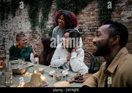 Smiling multiracial male and female friends talking with each other during dinner party Stock Photo