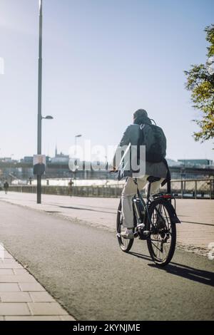 Businessman riding bicycle on lane during sunny day Stock Photo