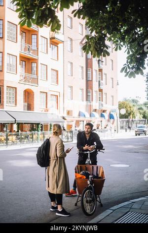 Male and female business colleagues talking to each other at roadside Stock Photo