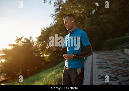 Attractive strong runner resting after self training using mobile phone Stock Photo