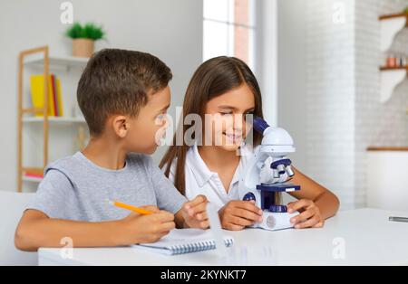 Little brother and sister together doing some experiments with microscope at home. Stock Photo