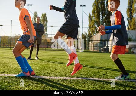 Group of boys running on green football field during training class Stock Photo