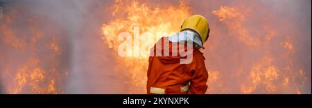 Firefighter Rescue training to stop burning flame, Fireman wear hard hat and safety uniform suit for protection burn using hose with chemical water fo Stock Photo