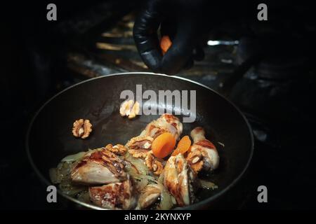 Chicken is cooked in a pan with nuts and dried apricots Stock Photo