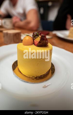 Piece of RAW, vegan mango mousse cake on the gold plate. Stock Photo