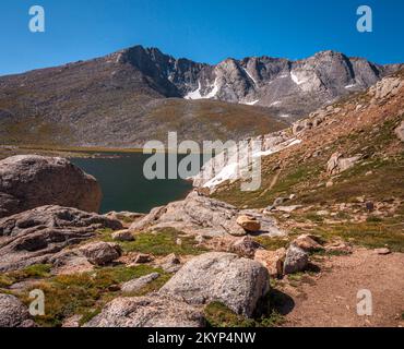 The rocky rugged shoreline of Summit Lake on Mount Evans, Colorado beneath a summer sky. Stock Photo