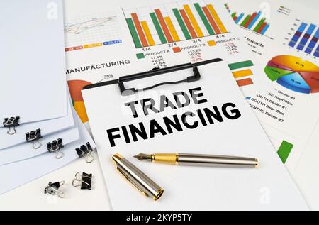 Business concept. On the table among financial graphs and charts lies a tablet with the inscription - TRADE FINANCING Stock Photo