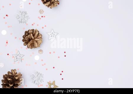 Christmas background with golden pine cones, stars and snowflakes on white background with copy space, top view. Stock Photo