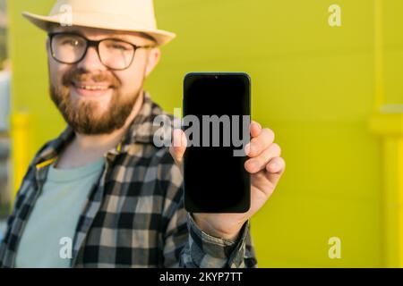Hot offering. Happy guy holds cellphone with black copy space and smiling. Human emotions facial and place for advertising and text Stock Photo