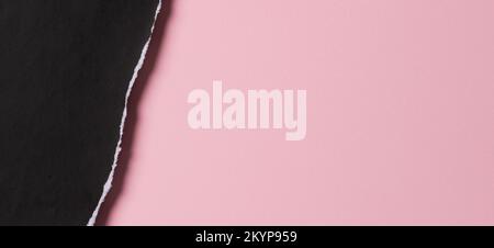 Black grunge ripped torn paper piece with ragged edge on pastel pink color paper background. Top view, copy space Stock Photo