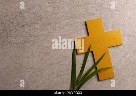 Image of close up of yellow wooden cross, palm leaf and copy space on grey background Stock Photo