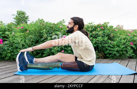 Hispanic athlete with leg prosthesis stretching on yoga mat Stock Photo