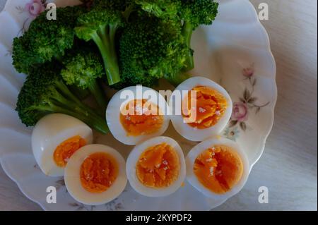 Boiled eggs, cut in half with bright orange yolks, and freshly blanched broccoli served at breakfast at home in Japan. Stock Photo