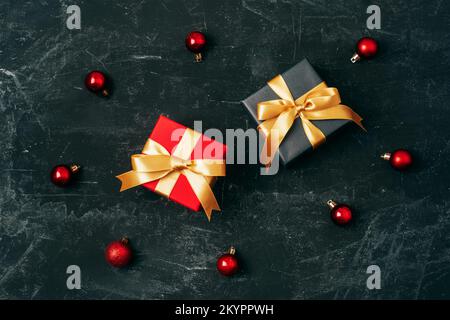 Two gift boxes and red Christmas balls on black background. Top view, flat lay Stock Photo