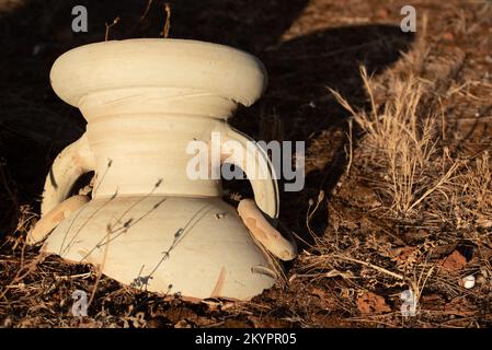 Close-up of an old clay jug that has been broken. The craw lies on the parched earth in the evening sun. Stock Photo