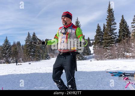 Happy middle aged man in insulated ski wear, arms lifted, walking in snow during Chama Chile Ski Classic in San Juan Mountains near Chama, New Mexico. Stock Photo